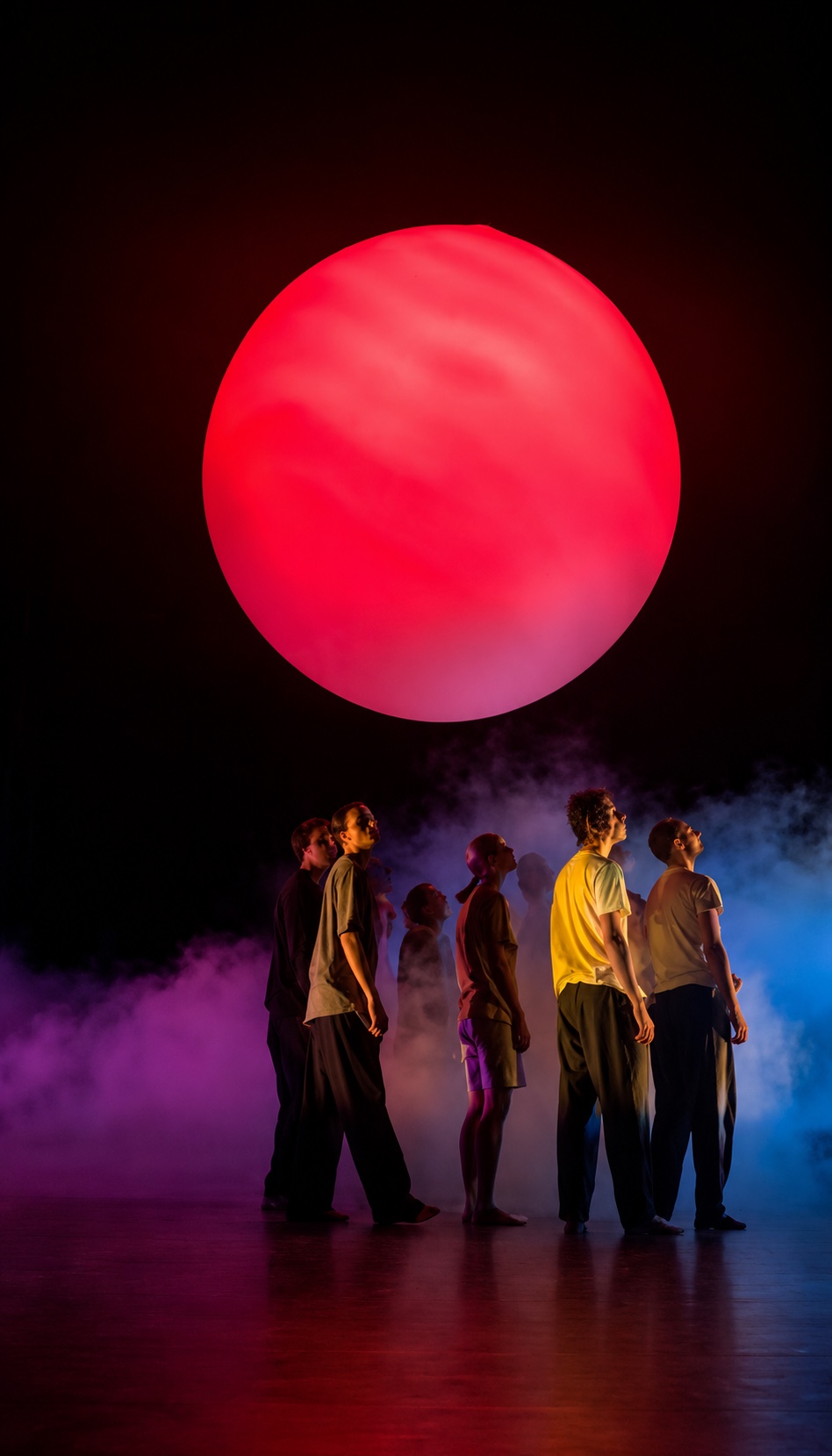 Grande sphère lumineuse rouge suspendue au-dessus des danseurs de La Marche Bleue