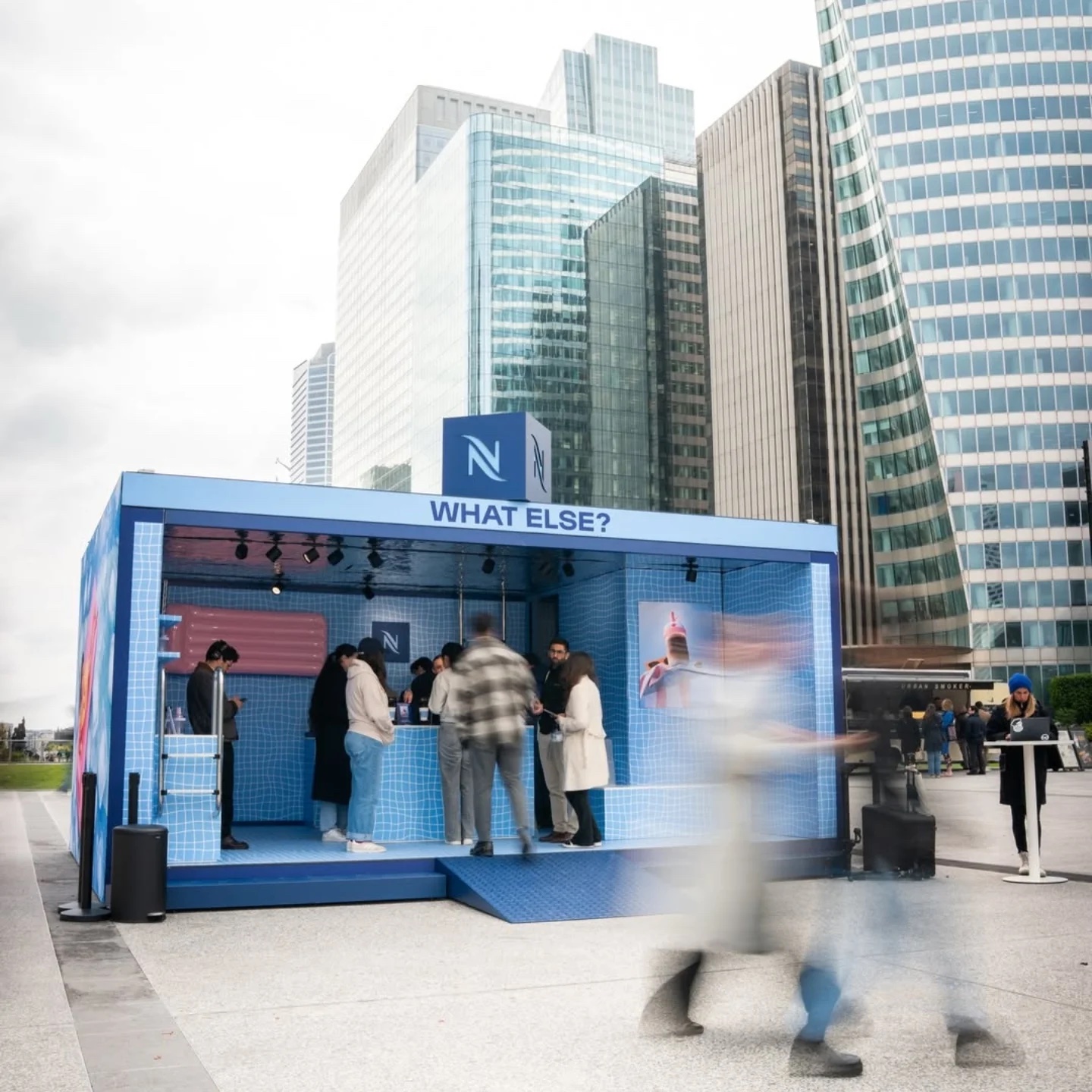 Kiosque bleu Nespresso avec le décor gonflable rose visible à travers l’ouverture